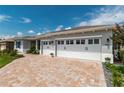 Close up of the three-car garage and brick-paved driveway with beautiful landscape at 9886 Sw 104Th Ave, Ocala, FL 34481