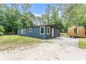 Inviting single-story home with blue siding, complemented by mature trees and a concrete driveway at 16082 Sw 24Th Pl, Ocala, FL 34481