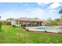 Spacious backyard features a covered patio, inground pool, and lush greenery, perfect for outdoor entertaining at 460 E Haines Blvd, Lake Alfred, FL 33850