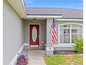 Inviting front entrance with a decorative red door, complimented by an American flag and well maintained landscaping at 63 Walnut Crse, Ocala, FL 34480