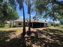 Backyard view, featuring an expansive screened lanai, mature trees, and a partially fenced in yard at 8100 Sw 56Th Ter, Ocala, FL 34476