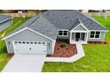 An aerial of a single-story home with a two-car garage, manicured lawn, and tasteful landscaping at 8289 Se 159Th Ln, Summerfield, FL 34491