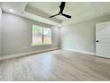 Bright bedroom featuring tray ceilings, ceiling fan, large windows, and light gray flooring at 8289 Se 159Th Ln, Summerfield, FL 34491