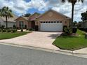 Charming home featuring a lush lawn, mature trees, and a brick-paved driveway leading to a two-car garage at 8781 Sw 82Nd Court Rd, Ocala, FL 34481