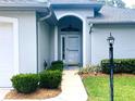 Close-up of the home's light blue front door, complete with an arched entryway, and manicured landscaping at 9328 Sw 192Nd Court Rd, Dunnellon, FL 34432