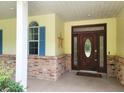 Charming front porch with a decorative wood door, brick accents, and a welcoming entryway at 95 Hickory Loop, Ocala, FL 34472