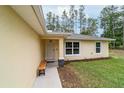 Inviting front door of a yellow home with manicured lawn and a small bench at 13131 Sw 73Rd St, Ocala, FL 34481