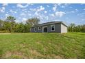 This home features a spacious backyard with a grassy area and a sliding glass door entrance at 142 Guava Pass, Ocklawaha, FL 32179