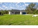 Charming single-story home with a blue garage door, gray exterior and a well-manicured lawn at 142 Guava Pass, Ocklawaha, FL 32179
