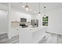 Modern kitchen featuring an island with quartz countertops, stainless steel appliances, and gray wood flooring at 162 Nw 42Nd Pl, Ocala, FL 34475