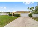 Single-story yellow home with a two-car garage and expansive driveway and fenced yard at 16605 Sw 31 Cir, Ocala, FL 34473