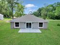 A spacious grassy backyard with a concrete patio and sliding glass doors for seamless indoor-outdoor living at 3696 Se 139Th Ln, Summerfield, FL 34491