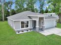Beautifully landscaped front yard featuring a gray home with stone accents, a large window, and manicured lawn at 3696 Se 139Th Ln, Summerfield, FL 34491