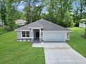 Charming single-story home with a gray facade, landscaped front yard, and two car garage nestled among mature trees at 3696 Se 139Th Ln, Summerfield, FL 34491