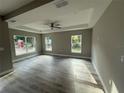 Bright living room featuring tray ceilings, a ceiling fan, and large windows that provide ample natural light at 3696 Se 139Th Ln, Summerfield, FL 34491