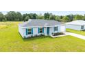 Single-story home with a manicured lawn, attractive blue shutters, and a convenient attached one-car garage at 37 Teak Run, Ocala, FL 34472