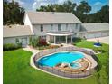 Backyard view showcasing an in-ground pool and hot tub surrounded by lush landscaping and a safety fence at 5765 Nw 110Th St, Ocala, FL 34482