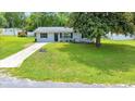 Single-story home with a well-maintained front yard, lovely landscaping and a large shade tree at 6511 Se 25Th Ave, Ocala, FL 34480