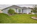 Single-story home with a well-maintained lawn, complemented by attractive landscaping and a flowering tree at 6877 Minchew Cir, The Villages, FL 34762