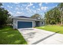 Beautifully landscaped front yard leads to a modern home featuring a blue garage door and gray exterior at 75 Guava Ter, Ocklawaha, FL 32179