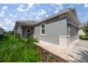 The home features a textured gray exterior, a covered front porch and manicured landscaping around the walkway at 7881 Sw 89Th Cir, Ocala, FL 34481