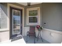 Cozy front porch featuring a decorative glass front door, chair, and small table with flower arrangement at 7881 Sw 89Th Cir, Ocala, FL 34481