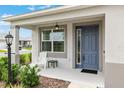 Charming front porch features a blue entry door, a comfortable seating area, and stylish outdoor lighting at 8802 Sw 79Th Loop, Ocala, FL 34481