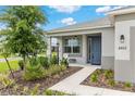 Inviting front porch with a classic blue door, enhanced by tasteful landscaping and exterior lighting at 8802 Sw 79Th Loop, Ocala, FL 34481