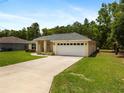 Charming single-story home with a well-manicured lawn, a two car garage and mature landscaping at 9432 Se 159Th Ln, Summerfield, FL 34491