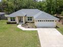 Charming single-story home with a well-manicured lawn, a two car garage and mature landscaping at 9432 Se 159Th Ln, Summerfield, FL 34491