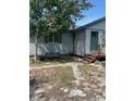 View of home exterior with wood siding, green shutters and door and a front bench at 1013 Nw Mandrake Dr, Dunnellon, FL 34431