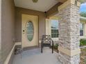 Inviting front porch featuring a stone column, chair, and decorative rug at 11 Pecan Course Loop, Ocala, FL 34472