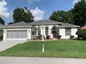 Charming single-story home with well-manicured lawn, a purple door, and a two car garage at 11605 Sw 69Th Cir, Ocala, FL 34476
