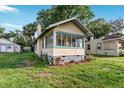 Quaint yellow single-story home featuring a charming sunroom and well-maintained lawn at 1434 Se Silver Springs Pl, Ocala, FL 34471