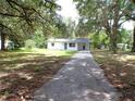 Charming single-story home with a long driveway and well-maintained lawn surrounded by lush greenery at 3418 Se 94Th St, Ocala, FL 34480