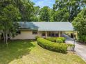 A single-story home featuring a metal roof, a long, covered carport, and manicured landscaping at 3621 Se 12Th Pl, Ocala, FL 34471