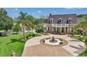 Aerial view of a brick home with a circular driveway, fountain, well manicured lawn, and tropical landscaping at 4550 County Road 104, Oxford, FL 34484