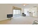 Open living room with neutral carpet, ceiling fan, and sliding glass door to the lanai at 5551 Nw 25Th Loop, Ocala, FL 34482