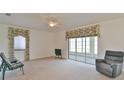 Bright living room with neutral carpeting, large windows, and sliding glass doors to the lanai at 5551 Nw 25Th Loop, Ocala, FL 34482