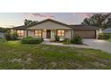 Inviting single-story home with warm exterior lighting, manicured landscaping, and attached two-car garage at 6320 Se 42Nd Ct, Ocala, FL 34480