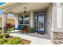 Charming front porch with seating, potted plants, and a decorative glass front door at 7891 Sw 89Th Cir, Ocala, FL 34481