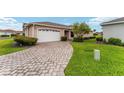 Charming home featuring a brick driveway, attached garage, manicured lawn, and beautiful landscaping at 8670 Se 141St Pl, Summerfield, FL 34491