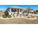 Inviting single-story home with a landscaped front yard, a covered porch with chairs, and a two-car garage at 8878 Sw 103Rd Cir, Ocala, FL 34481