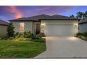 Charming single-story home with a well-manicured lawn and a two-car garage at twilight at 8989 Sw 57Th Place Rd, Ocala, FL 34481