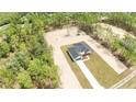 An aerial view of a new single-story house with a green garage door on a wooded lot at 12251 Sw 67Th Ln, Ocala, FL 34481