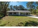 Charming single-story home featuring light gray siding, black shutters, a covered carport, and a lovely lawn at 16615 Se 63Rd Ln, Ocklawaha, FL 32179