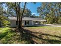 Cozy single-story home with light gray siding, black shutters, covered carport, surrounded by beautiful trees at 16615 Se 63Rd Ln, Ocklawaha, FL 32179