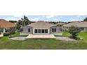 A screened-in enclosure on the back of the house leads to a concrete patio and grassy lawn at 2002 Enrique Dr, Lady Lake, FL 32159