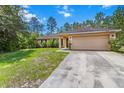 Exterior shot of the front of the house showcasing the attached garage and landscaping at 23340 Nw Columbine Ave, Dunnellon, FL 34431