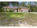 Exterior shot of the front of the house showcasing the attached garage and front yard at 23340 Nw Columbine Ave, Dunnellon, FL 34431
